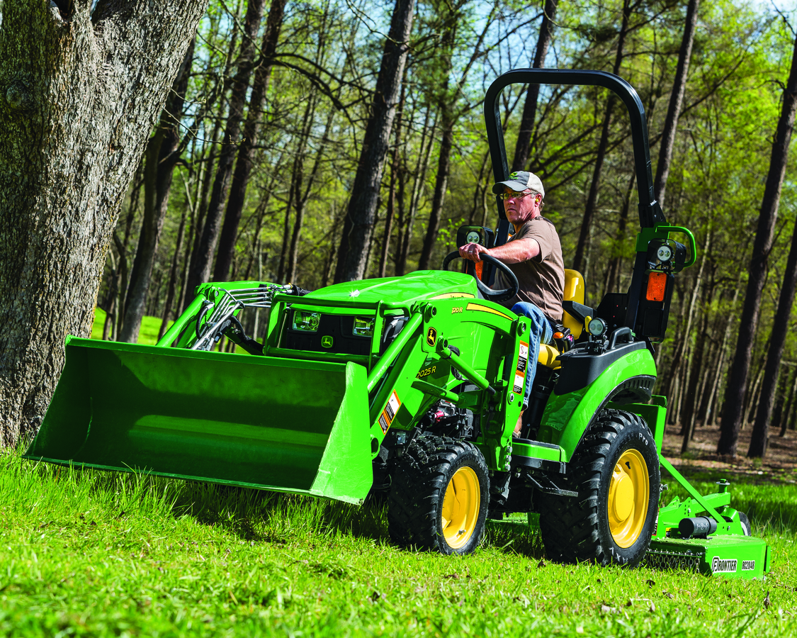 A man is driving a John Deere 2025R Utility Tractor 51810